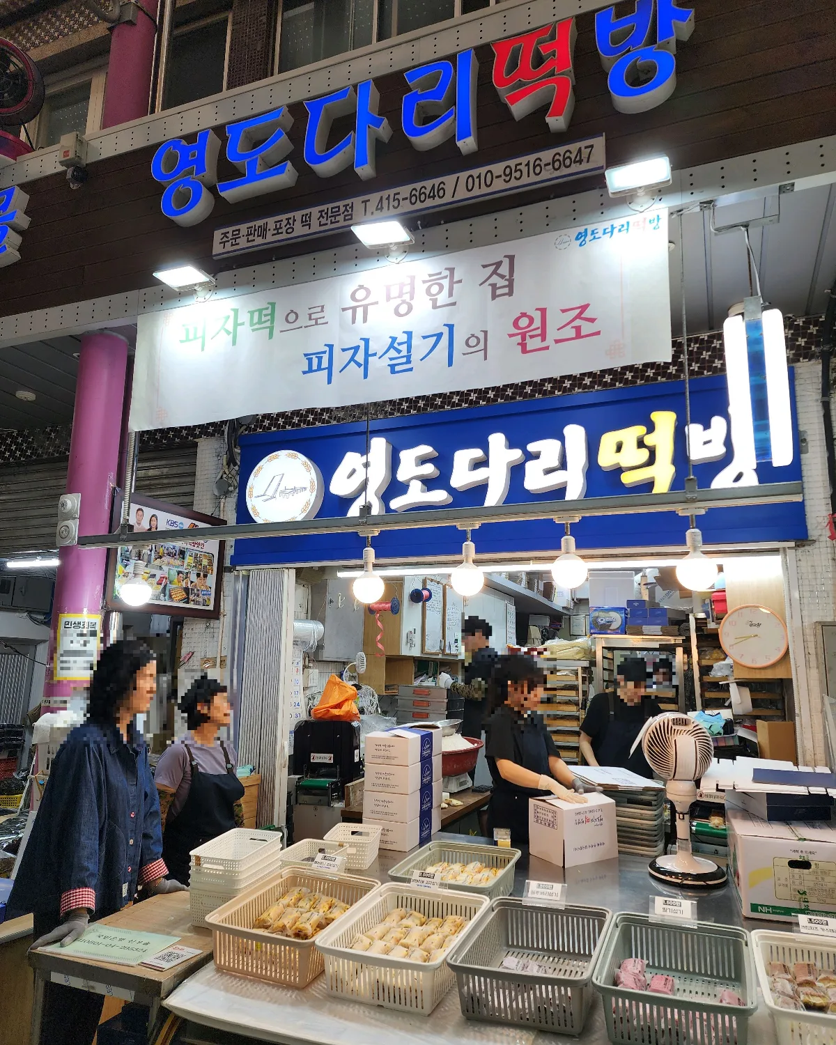 ヨンドダリトッパン — 青い店名看板と餅が並ぶ店先
