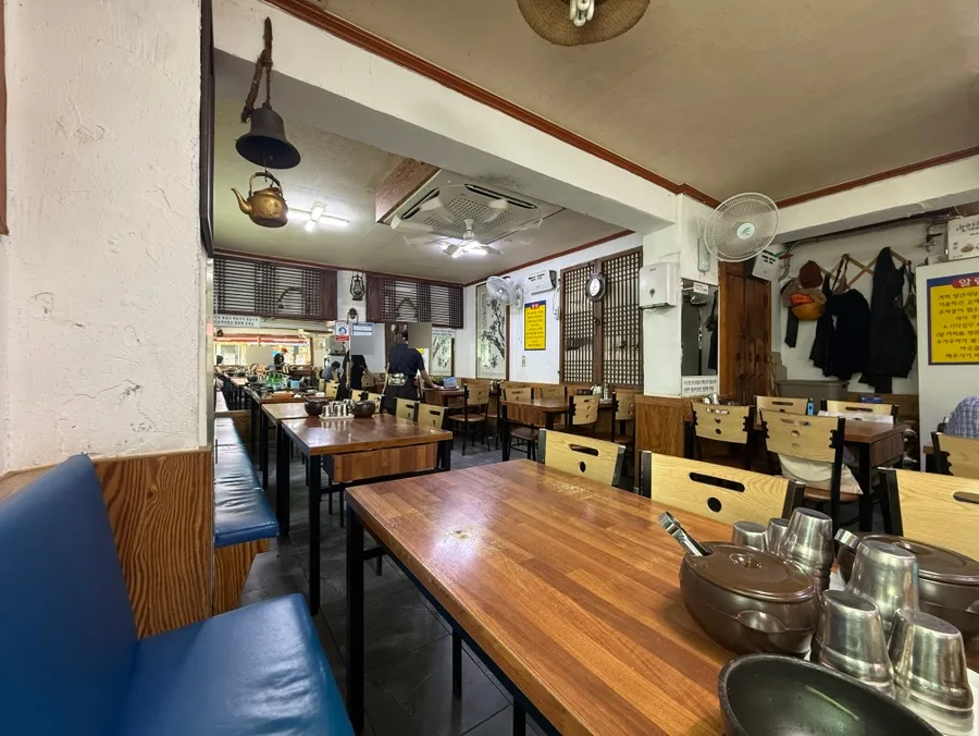 ヨンジンテジクッパ 本店 — 木のテーブルと青い長椅子