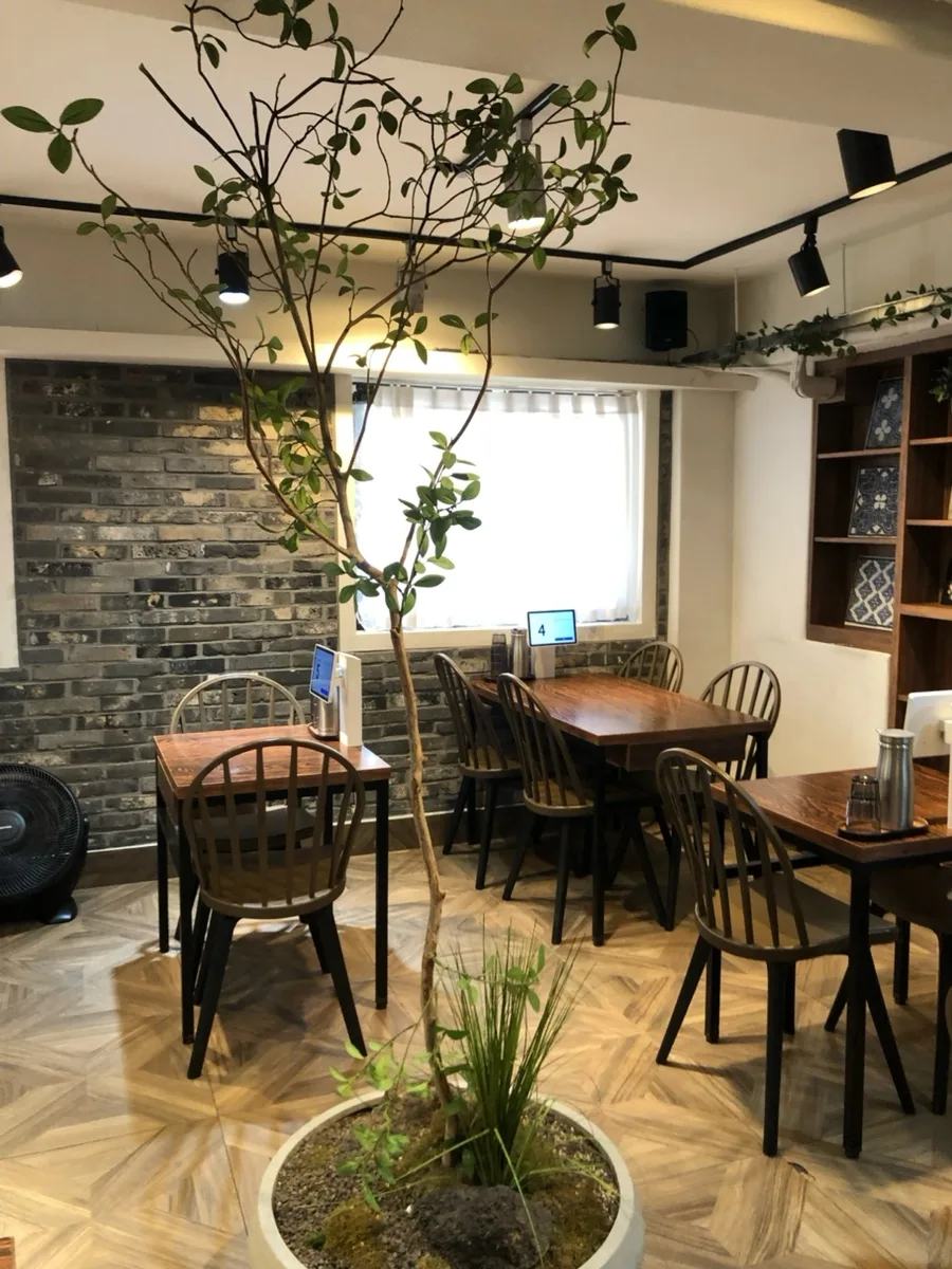 延南トマ 北村店 — 木のテーブルと中央の植木