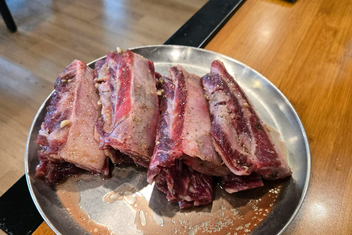 ヨンポカルビ — 銀皿に並ぶ味付けした骨付き肉