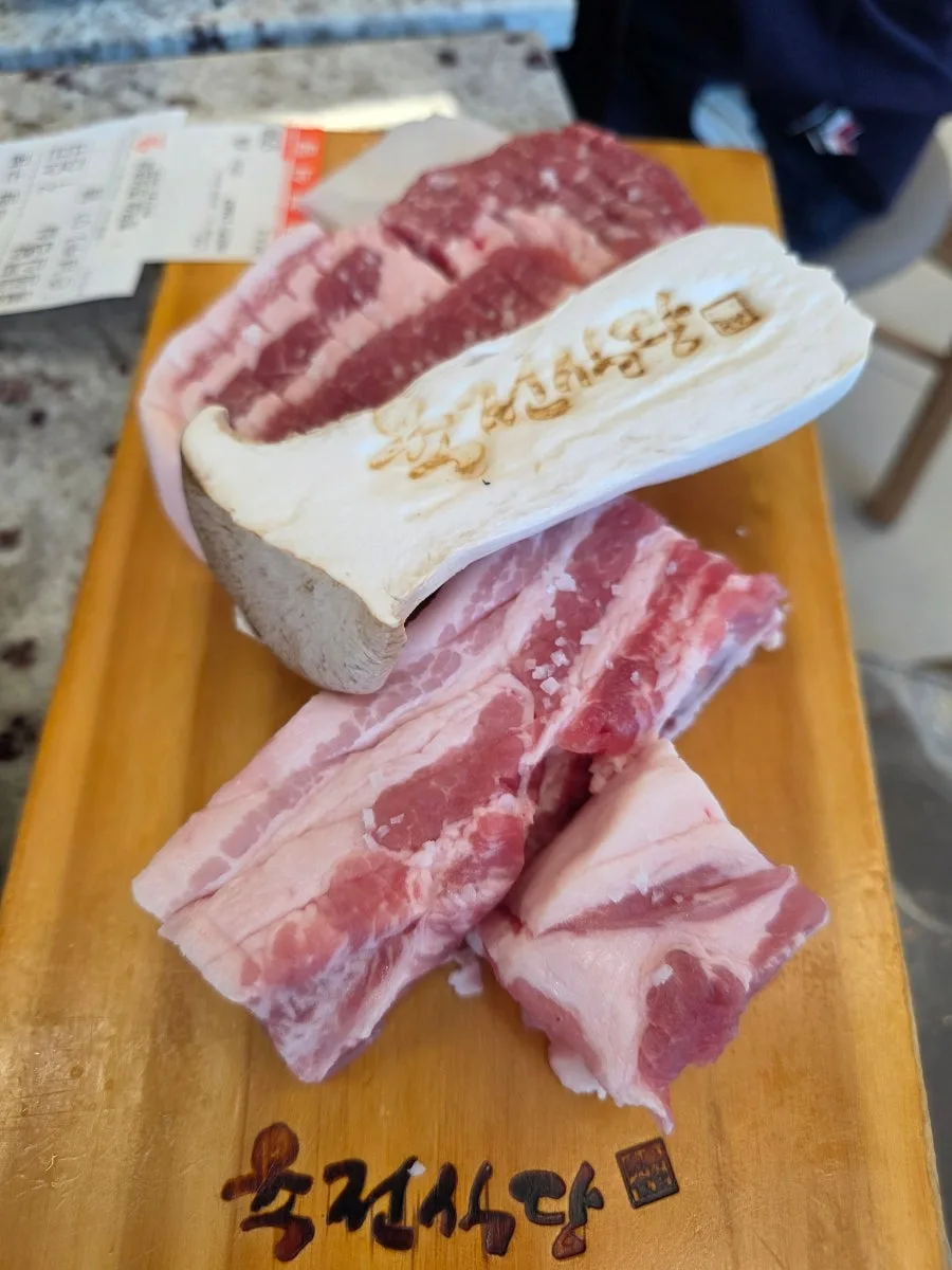 木の板にのった厚切りの豚バラ肉と焼印入りのエリンギ