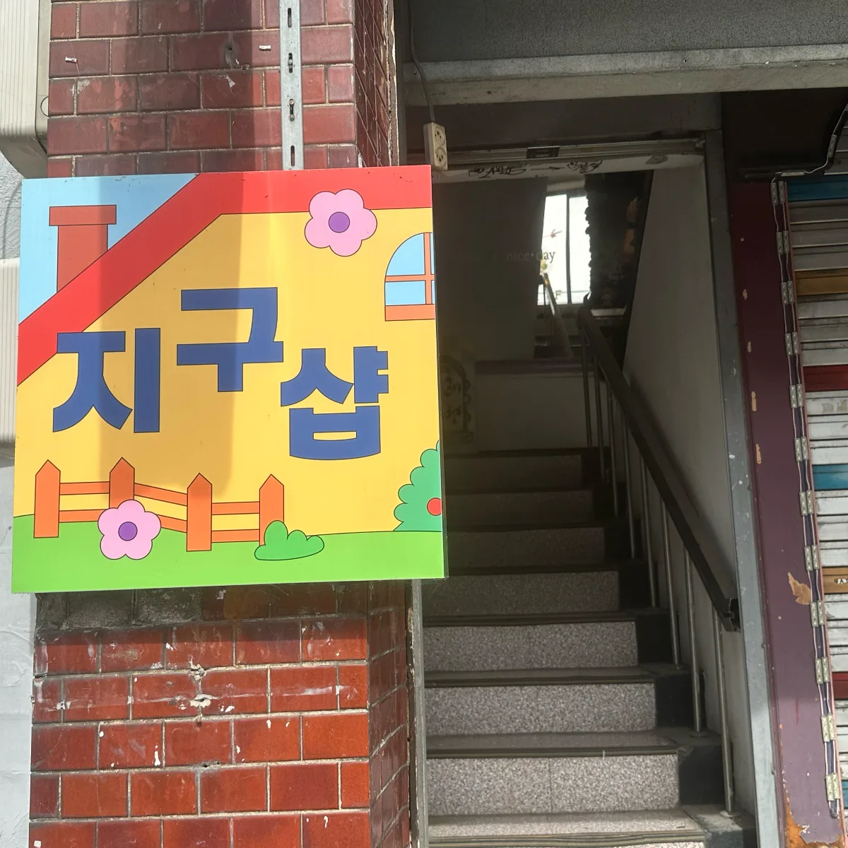 ZIGUSHOP 本店 — 黄色い店名看板と入口の階段